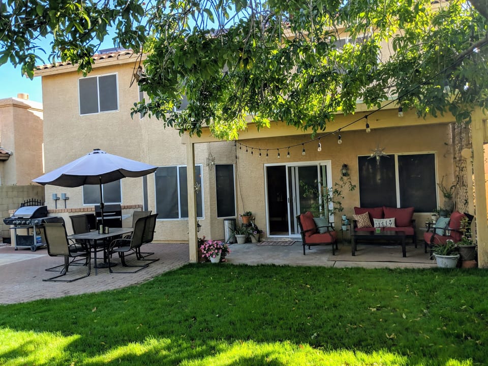 Backyard with plenty of seating, lights and grass for pets. 