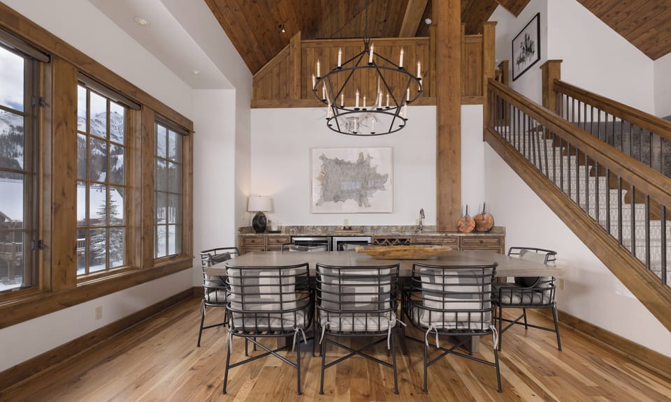 Gather around this stunning dining table where rustic wood beams meet modern elegance, perfect for your memorable mountain retreat meals.