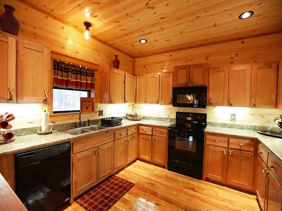 A fully equipped rustic kitchen combines modern convenience with warm wood cabinetry for effortless cabin living.