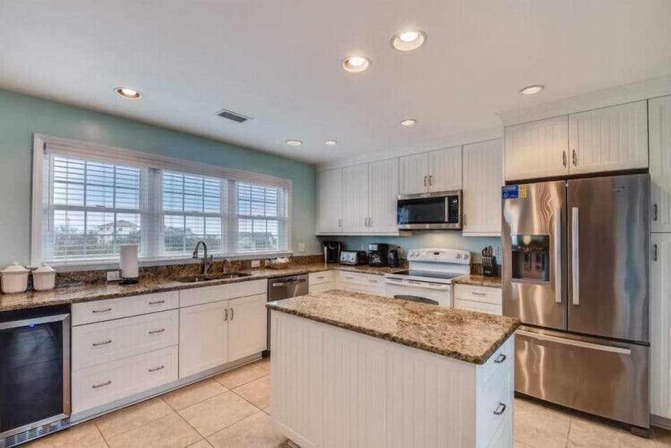 Your fully equipped kitchen features granite countertops, stainless appliances, and a spacious island—perfect for preparing meals and gathering with loved ones in bright, inviting style.