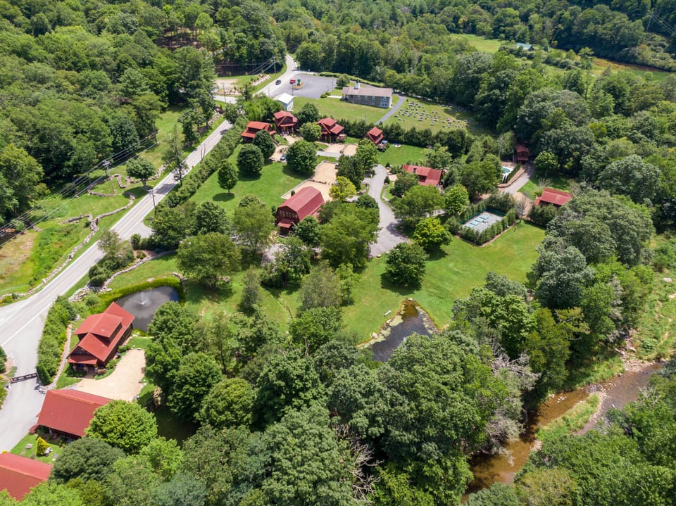 Lush green grounds, a fountain pond, and a winding creek surround the cabins at Moonlight View At Eagles Nest in Banner Elk.
