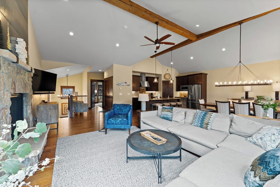 The spacious living area features ample seating around vaulted ceilings, a cozy stone fireplace, and a flat-screen TV.