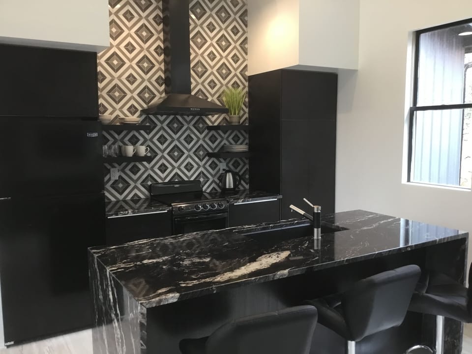 Full service kitchen with granite waterfall island and barstools