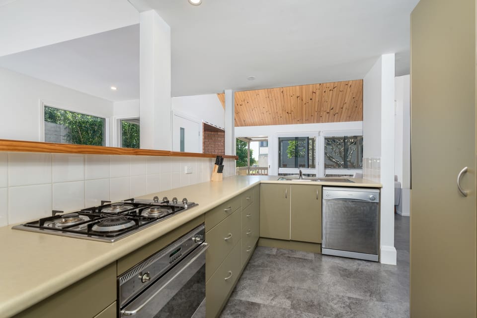 Kitchen with dishwasher, fridge, cooking utensils and cookware.