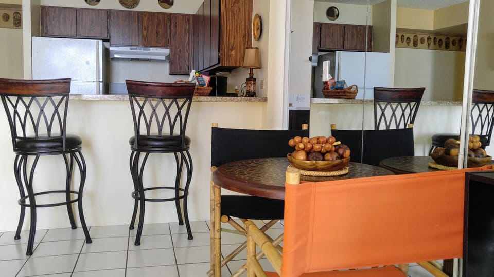 Dining table, chairs at breakfast bar, bathroom on right, mirror wall  on right