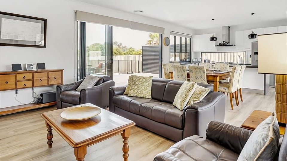 Living area with a comfy couch and relaxing lounge chairs along with large TV.