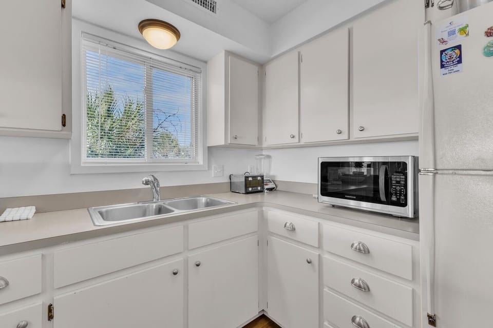 Your bright, fully-equipped kitchen features everything you need, from the spacious sink to modern microwave, all bathed in natural light.