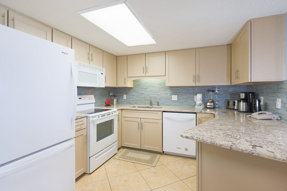 Prepare meals in this inviting kitchen, featuring granite countertops, white appliances, and a stylish backsplash