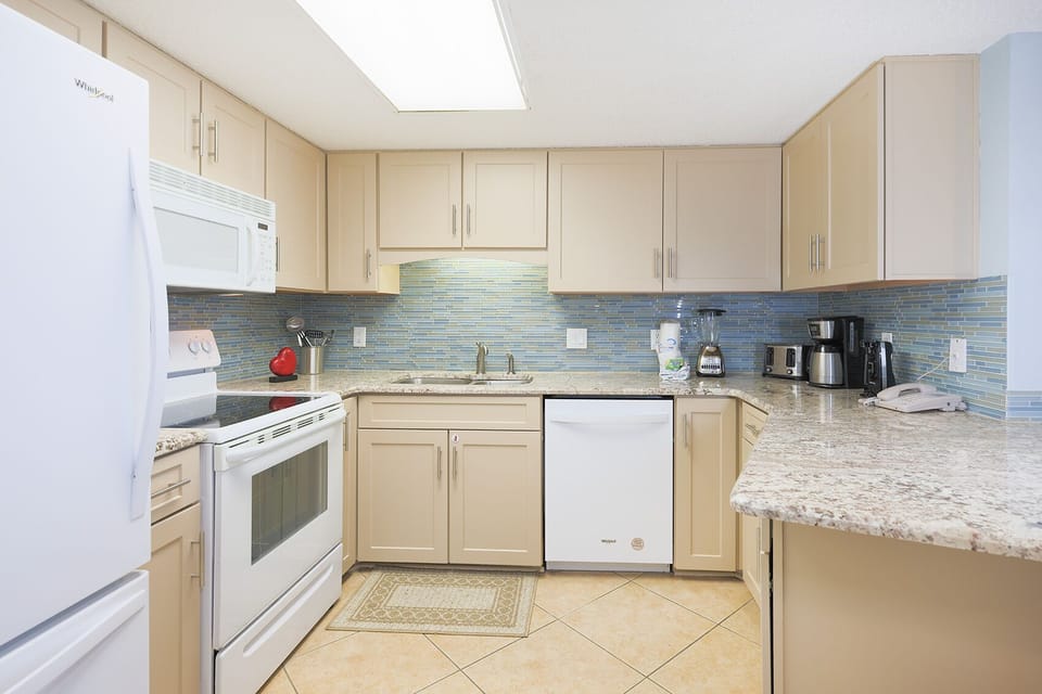 Enjoy cooking in this kitchen, featuring granite counters, white appliances, and a stylish backsplash