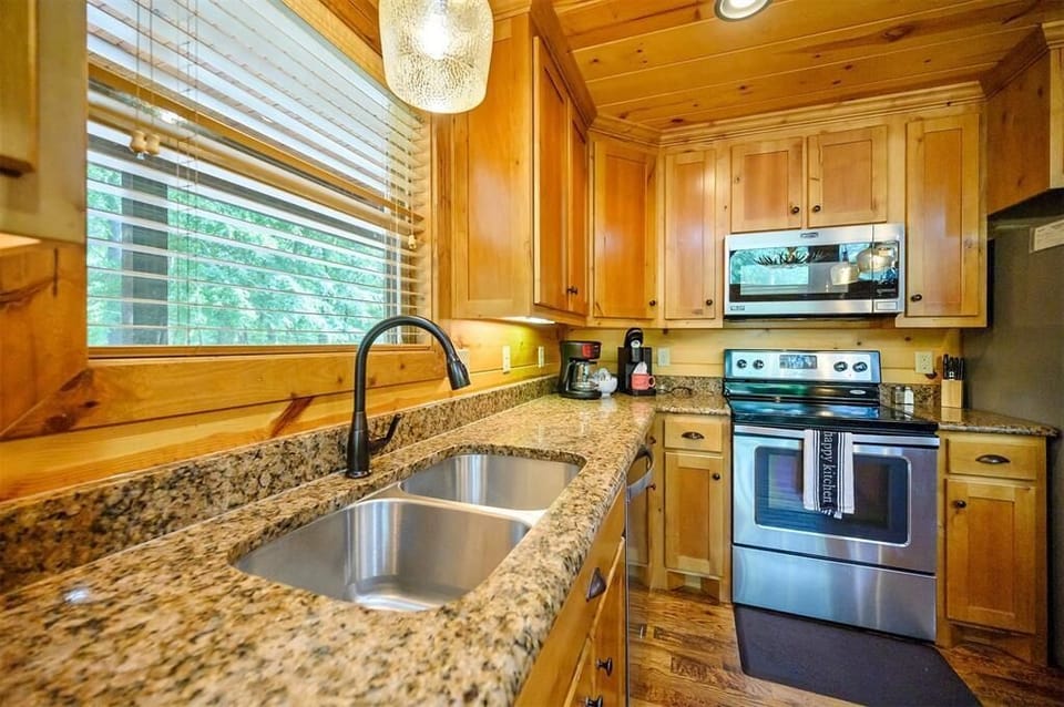 Your fully-equipped kitchen features warm wood cabinetry, granite countertops, and stainless steel appliances—everything you need to prepare meals at home with natural light streaming through the window.