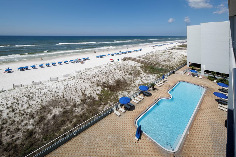 Balcony View - Direct views of the on-site pool and beach access from balcony