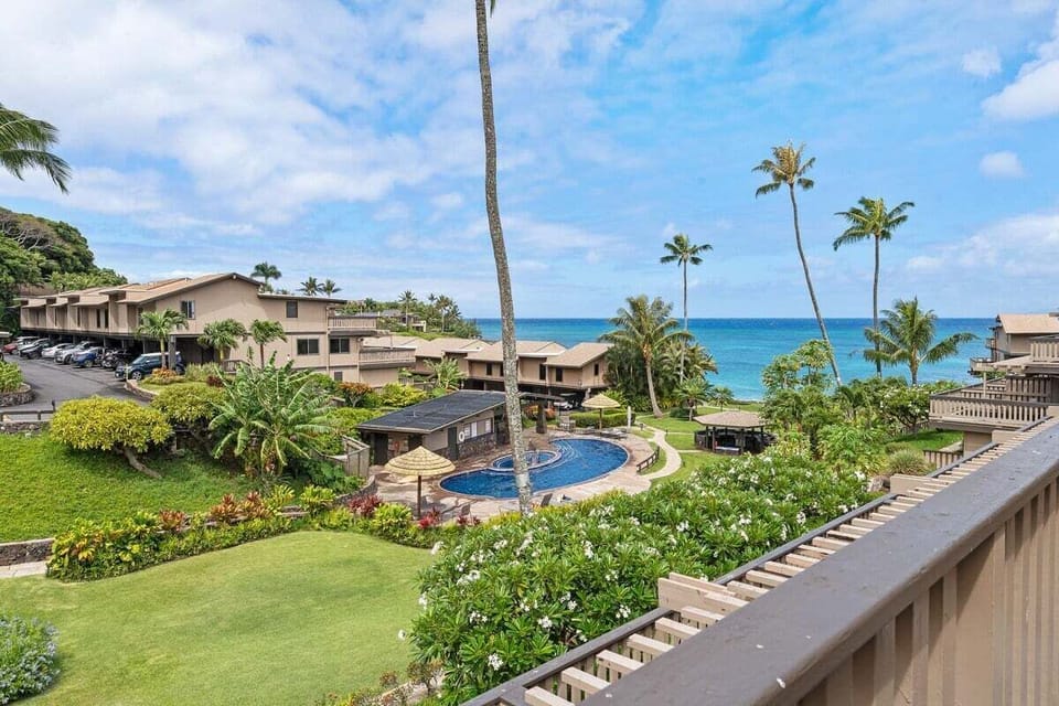 Stunning lanai view with lush tropical landscaping and swaying palm trees against a clear blue sky.