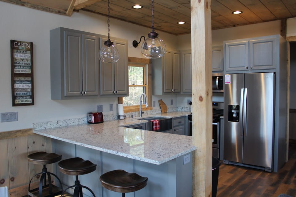 Open kitchen with granite countertops and bar with 3 stools.