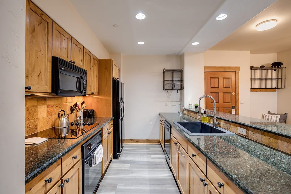 Whip up your favorite meals in this spacious galley kitchen featuring granite countertops, warm knotty pine cabinets, and modern appliances.