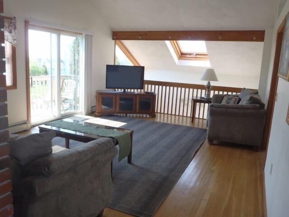 upstairs living room has sofa and two recliners and TV.  Ocean views from slider