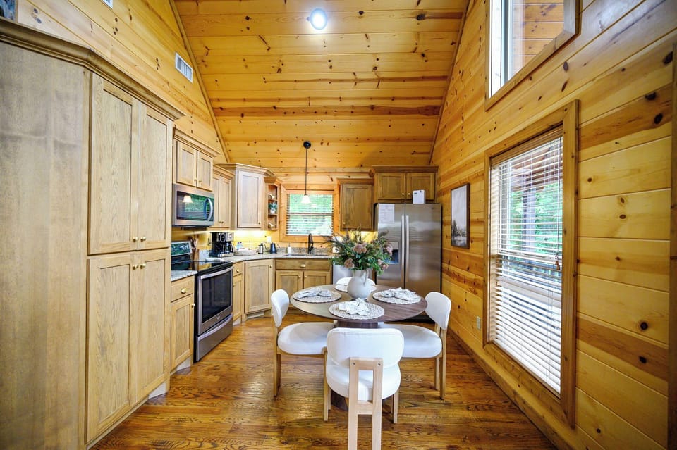 Cook your favorite meals in this rustic-modern kitchen with warm wood beams, full appliances, and bright windows overlooking nature.