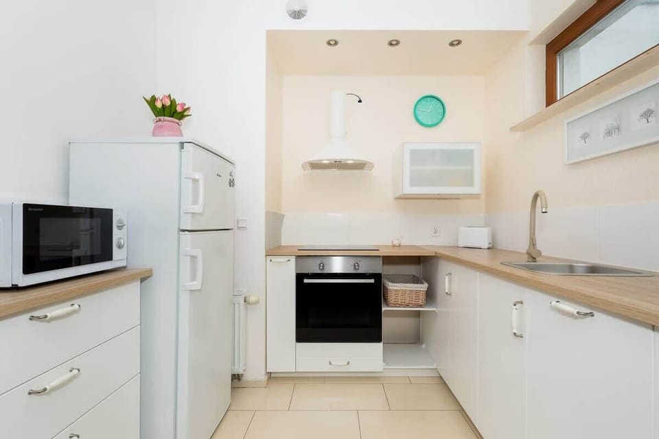 A kitchenette with white cabinets, a stove, and essential appliances, providing a clean and functional cooking area.