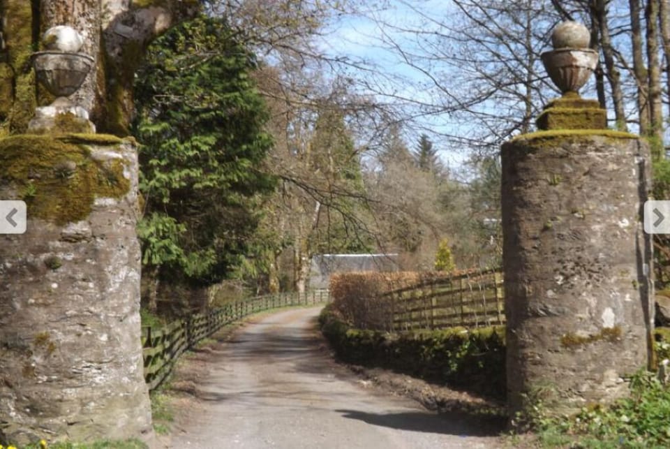 Cottage roof just visible through historic pillars at entrance to estate.