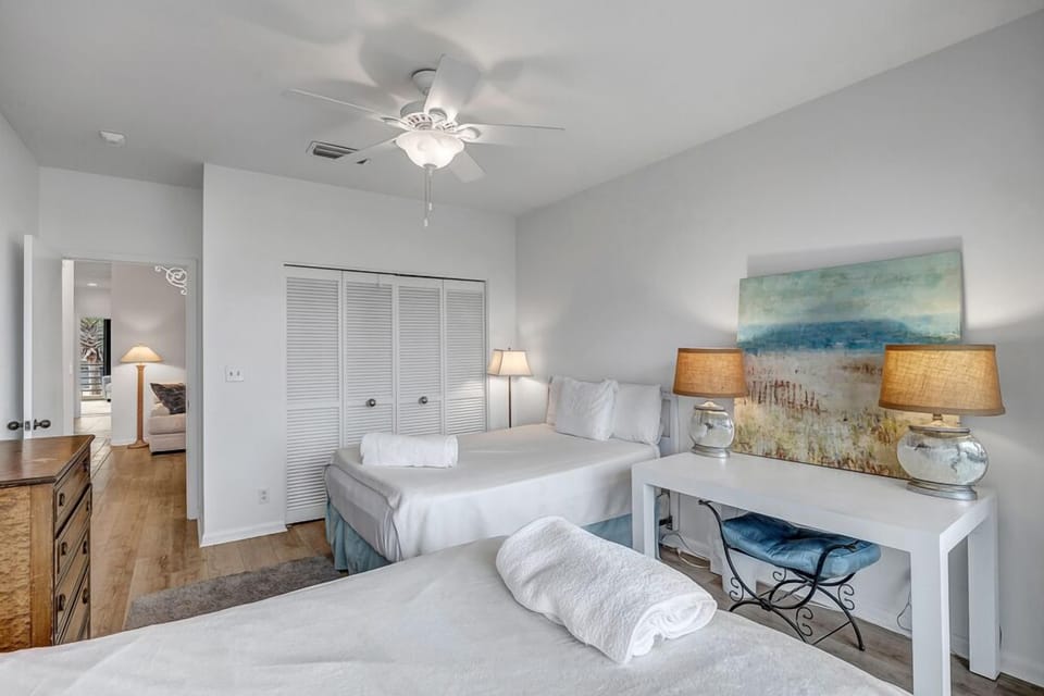 - Coastal guest room with sandy toned art, full closet, and white wood furnishings
- Perfect for sharing, with two beds and an additional writing desk by the window
- Peaceful retreat offering privacy, function, and easy access to the hallway