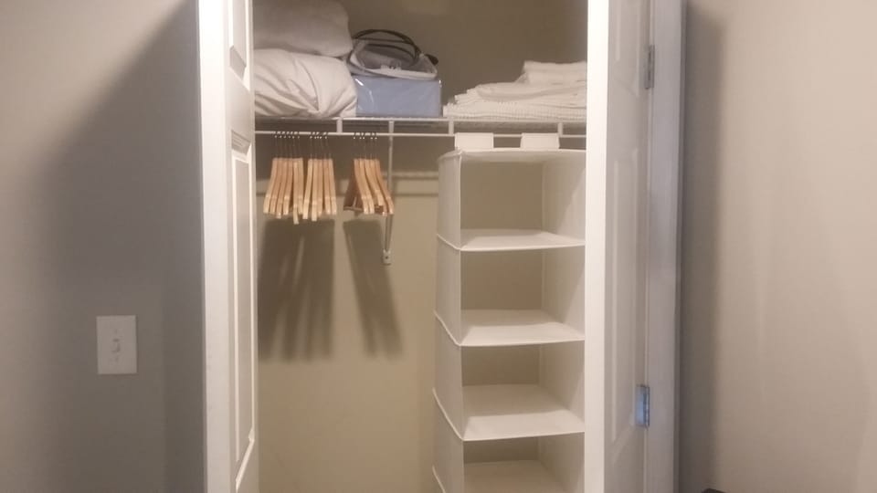 large closet with extra bedding and iron and ironing board