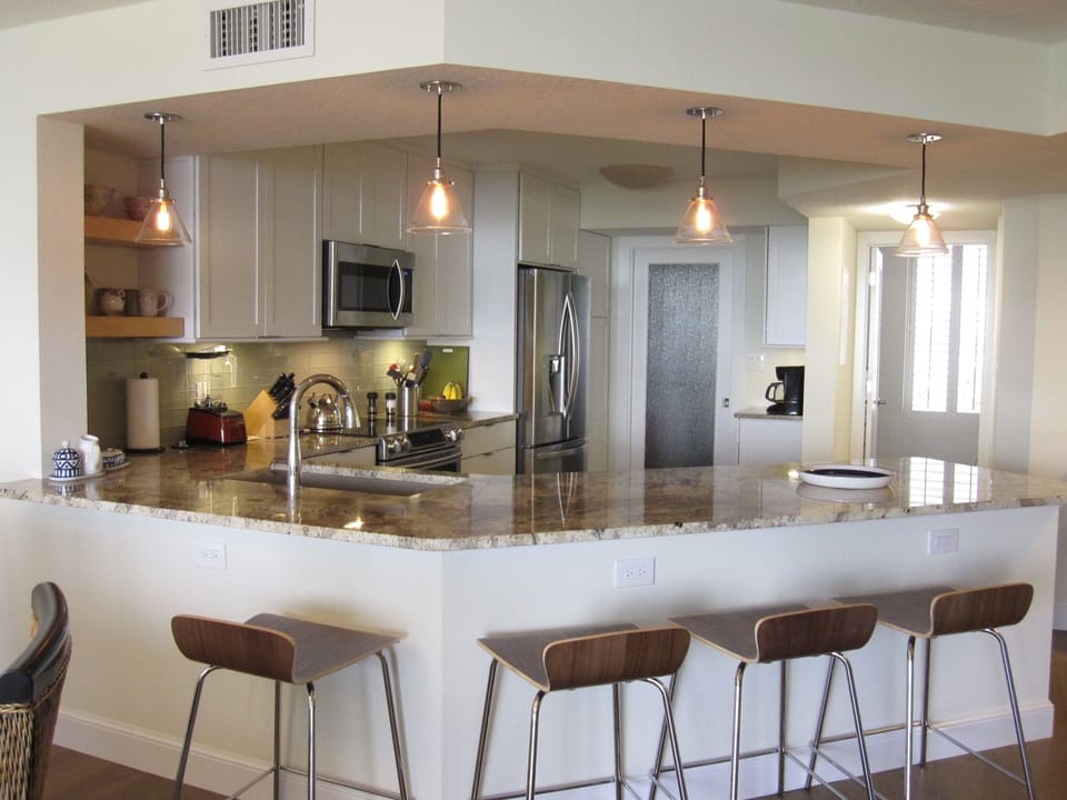 View of kitchen with bar stools. Full sized new washer and dryer  behind doors