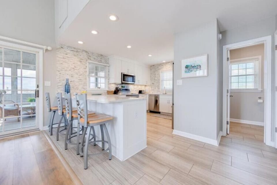 Step into your bright, open-concept kitchen with a stylish breakfast bar perfect for morning coffee and casual meals. Light wood floors and coastal-chic décor create a welcoming, airy feel while you prepare your favorite dishes.