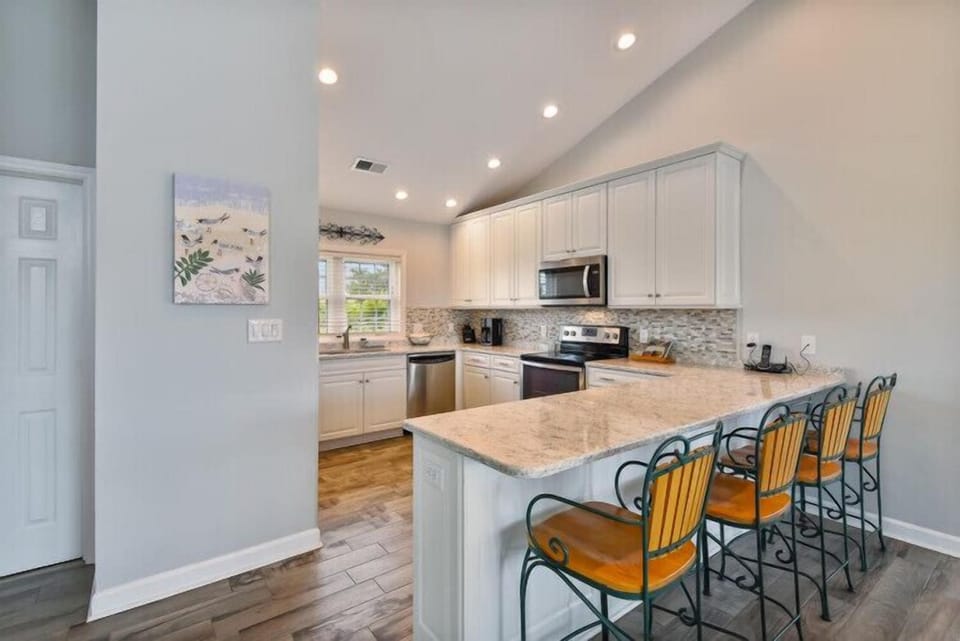 Step into your bright, modern kitchen with sleek white cabinetry, granite counters, and a spacious island where you can gather for meals and memories with family.