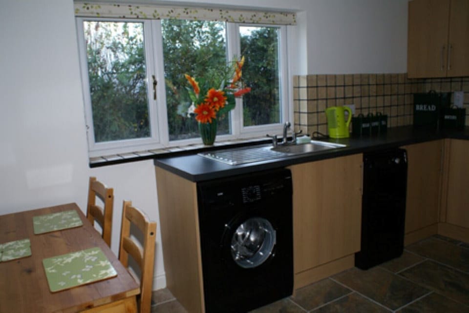 Kitchen area showing washing machine and position of chairs and table