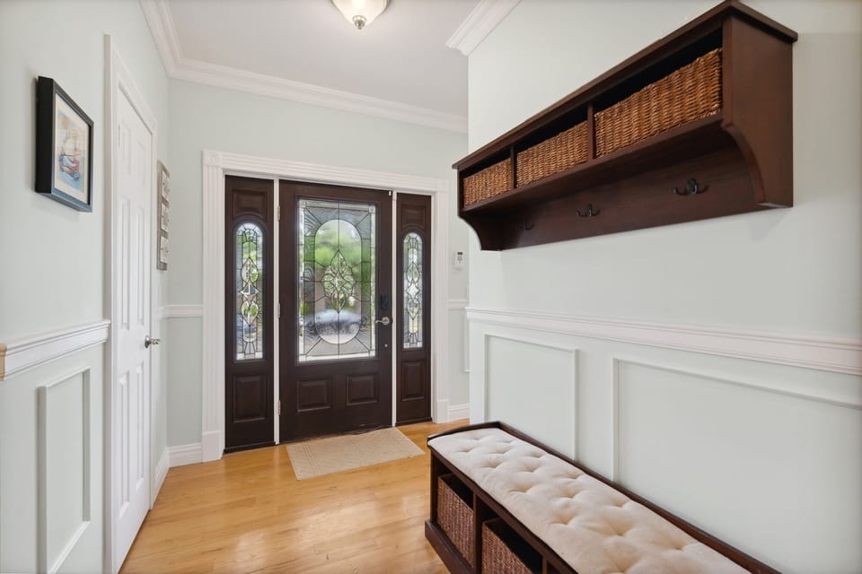 View of front door entry from stairs, showing changing bench, cabinetry.