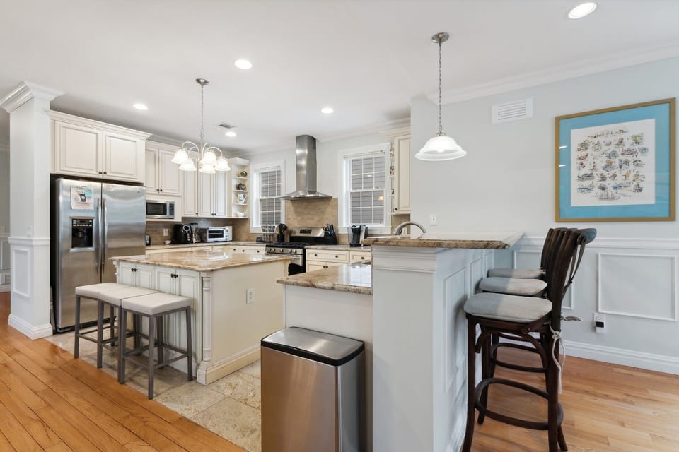 View of kitchen from great room, showing counter with three high stools. 