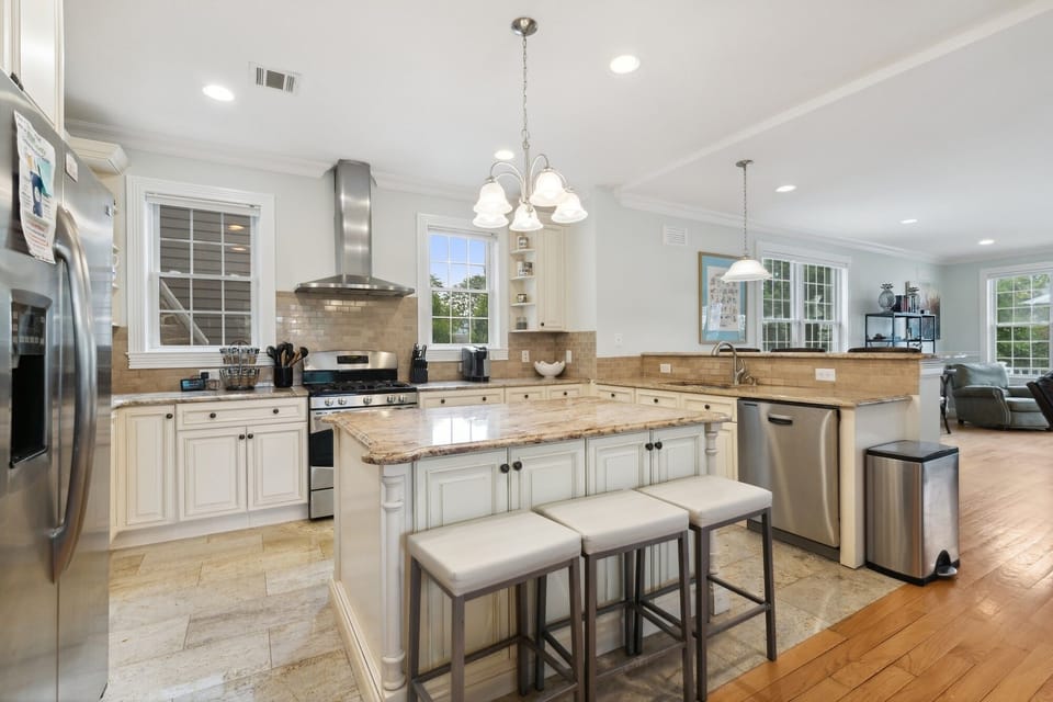 View of kitchen and island. Kitchen has air fryer, blender, waffle maker, etc.