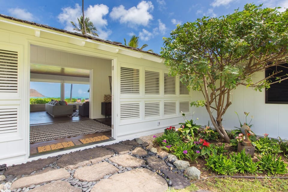 Welcome to your oceanfront retreat, where tropical landscaping, island-inspired architecture, and a peaceful garden path create a warm and inviting arrival experience.