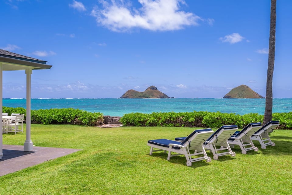 Oceanfront lawn with a view of the Mokulua Islands, lounge chairs overlooking turquoise waters and offshore islands under clear blue skies—an ideal retreat for relaxation.