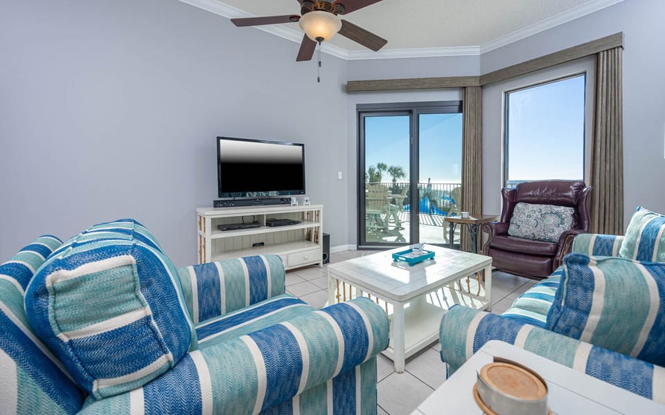 Relax in the inviting living area with cozy seating, a queen sofa sleeper, large TV, and beachfront balcony access