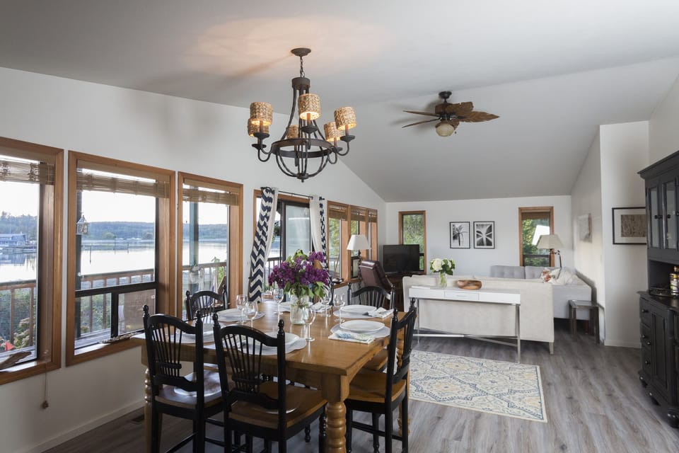 Open dining room, living room and kitchen with view of bay. Fire table on deck.