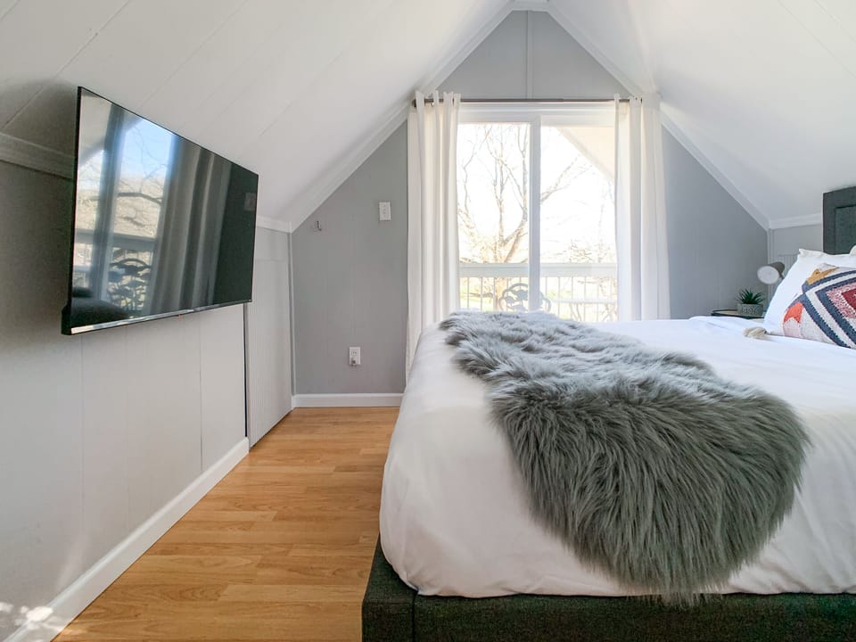 Bright and airy upstairs bedroom featuring a cozy queen size bed, Smart TV and access to the balcony to relax on after a long day.