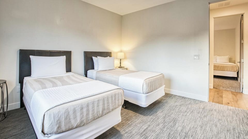 Comfortable bedroom with two twin beds, luggage rack, and a peaceful atmosphere.