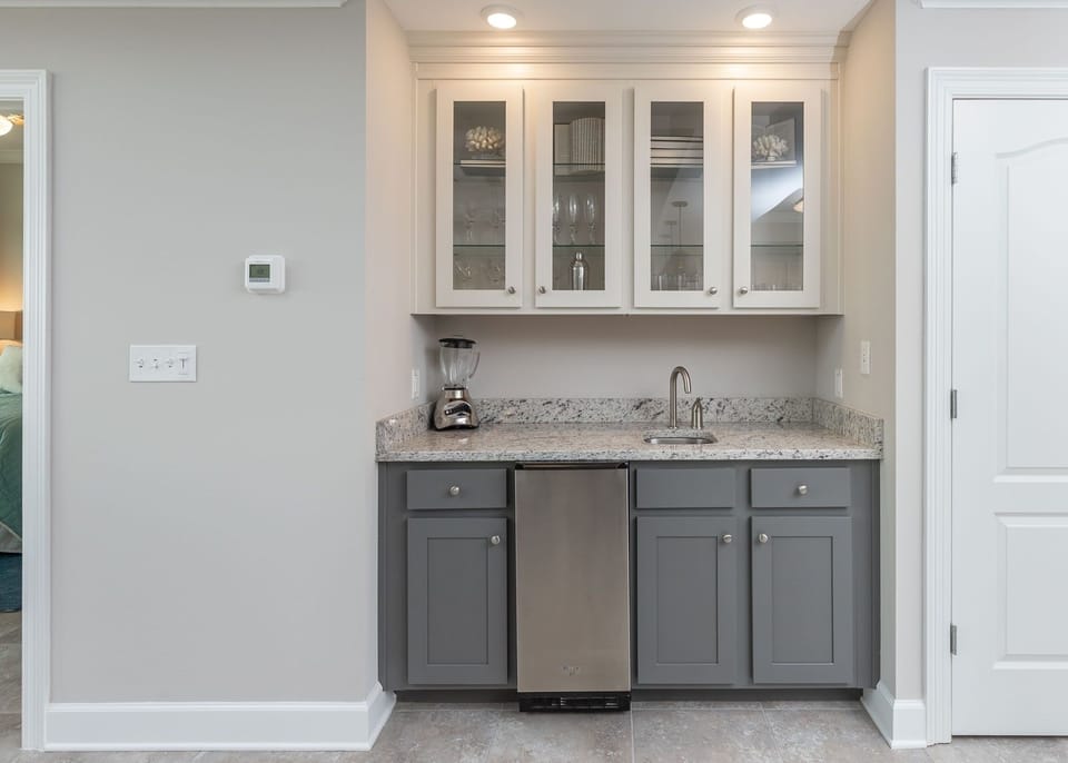 Craft refreshing drinks at the wet bar, enjoying easy access to glassware for memorable gatherings