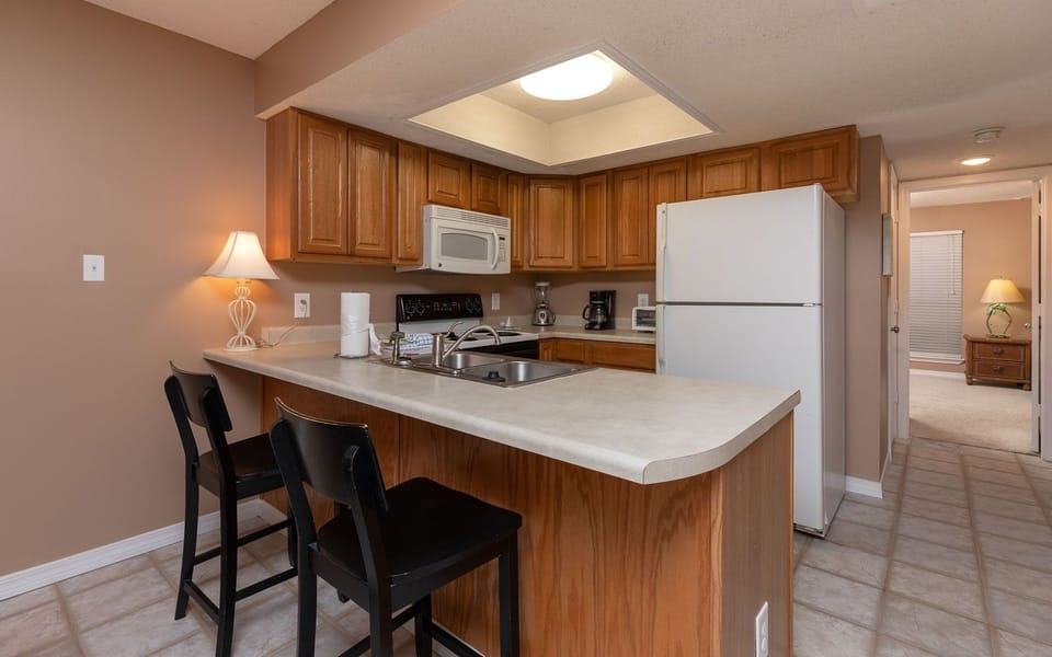 The kitchen features warm wood cabinets, a convenient breakfast bar, and essential appliances for a delightful experience