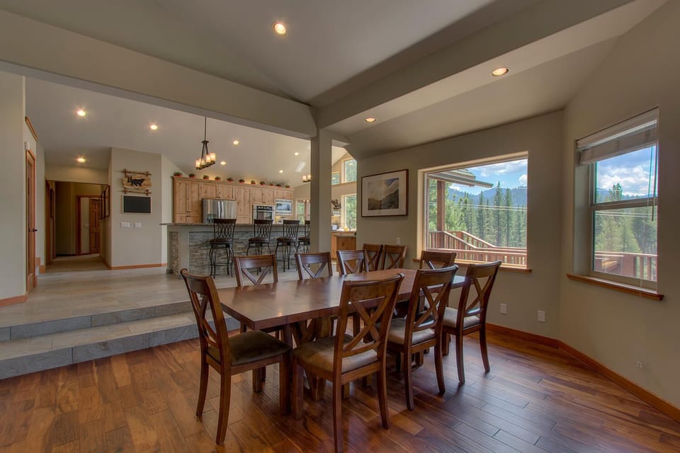 - Large dining table for family gatherings  
- Open-concept design connects kitchen and dining  
- Windows showcase mountain scenery all around