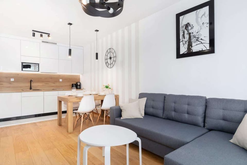 Another angle of the living room with a blue and gray sofa, TV, and minimalistic decor. Light wooden floors add warmth.