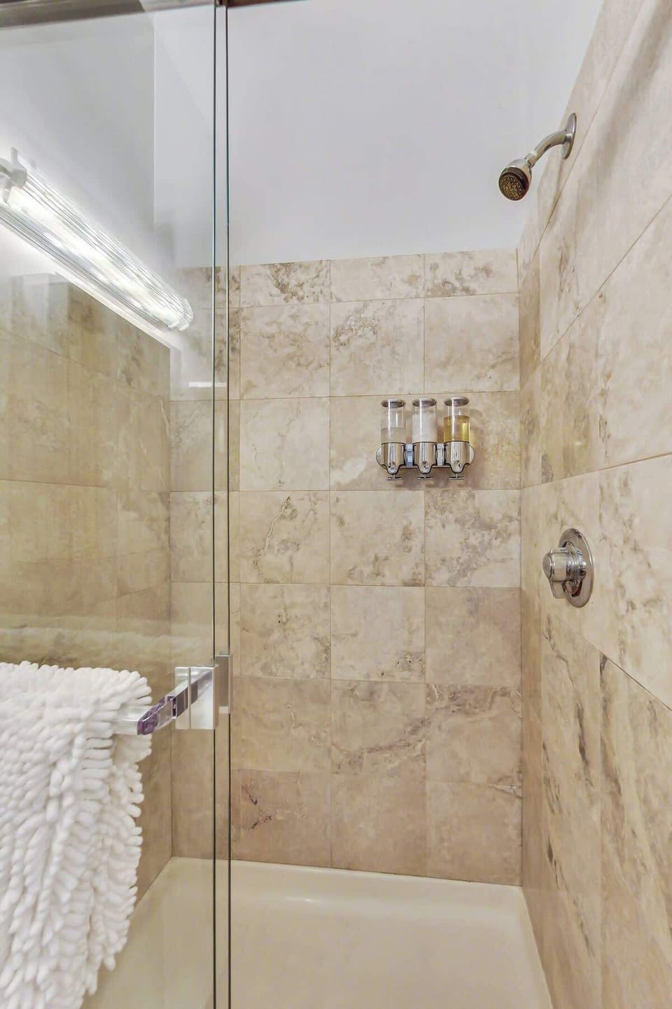 Spacious walk-in  shower with glass shower door.  Lots of light gets into the shower where you will enjoy Kiehl's bath products.