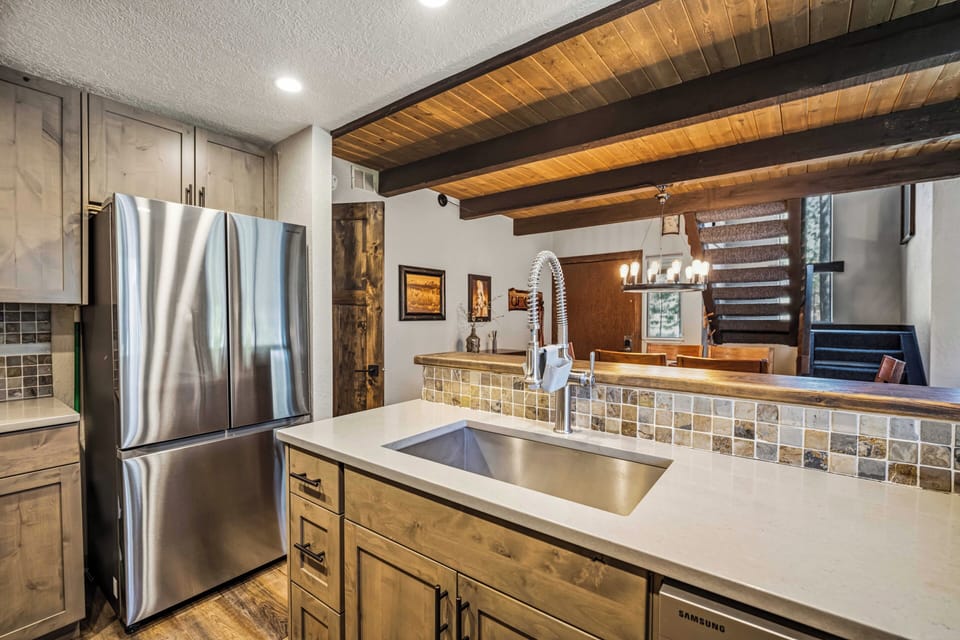 Step into your mountain retreat's gourmet kitchen, where exposed wood beams and modern stainless appliances blend rustic warmth with contemporary convenience for memorable meals.
