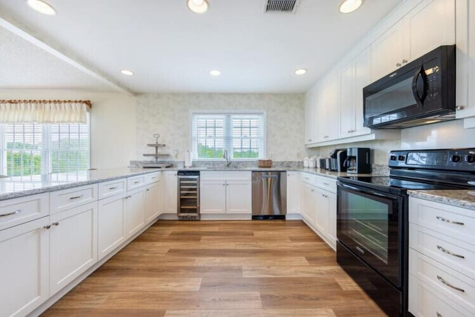 You'll love preparing meals in this bright, spacious kitchen with sleek white cabinetry, granite counters, stainless steel appliances, and beautiful hardwood floors that invite you to cook and gather comfortably.