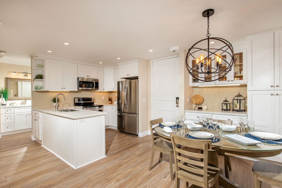 View of the dining room with designer light fixture and kitchen with recessed lighting.
