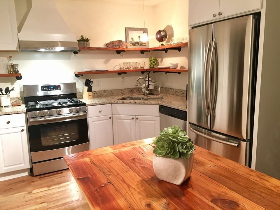 Open wood shelving, gas range and stainless appliances in the newly renovated kitchen 