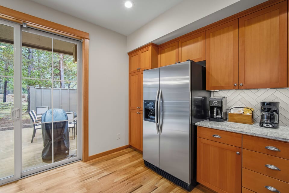 Your fully-equipped kitchen flows to a private patio, perfect for morning coffee and outdoor dining with nature views.