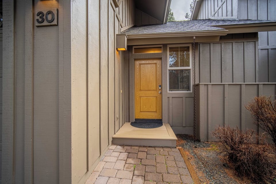 Contemporary entrance with warm wood door and paver walkway creates an inviting arrival at unit 30.