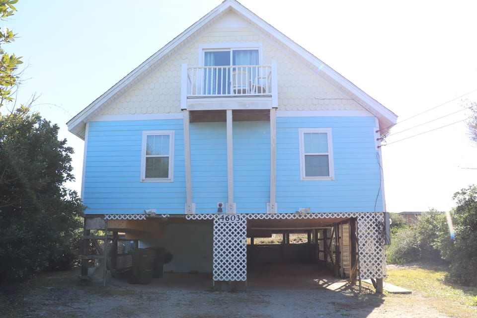 Charming coastal cottage elevated on stilts with a private balcony and covered parking beneath.