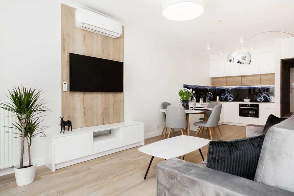 A spacious living room with a TV mounted on the wall, modern decor, and white furniture for a clean look.